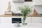 Cup of coffee, vase with cow parsley on white linen table cloth. Modern eclectic kitchen interior. White brick wall