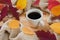 Cup of coffee, warm scarf and scattered autumn leaves on wooden table