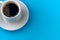cup with coffee on a white saucer on a blue background. Free space. flat lay