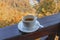 A cup of coffee on a wooden railing