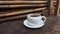 A cup of coffee on a wooden table against a backdrop of bamboo piles