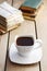 Cup of coffee on wooden table. Vintage books and pile of letters