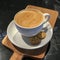 A cup of creamy aromatic flat white coffee serve on a wooden plate