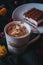 A cup of dalgona coffee with piece of tiramisu cake isolated on green knit whit autumn flowers