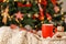 Cup of delicious hot cocoa on tray against blurred Christmas tree