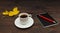 Cup of espresso, black pocketbook, pen and autumn yellow leaf on wooden table