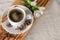 A cup of espresso, cinnamon sticks, anis stars and white carnations on wooden desk and textile background.  Good morning! Copy