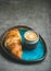 Cup of espresso and croissant in blue tray, grey background