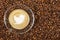 Cup of espresso with flying bird sign on coffee foam on coffee beans background. With copy space