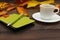 Cup of espresso, green notebook and pen among autumn leaves on wooden table