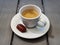 Cup of espresso with small chocolate praline on rustic gray table