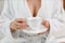 Cup in female hands on background bust in white bathrobe