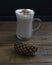 Cup of fragrant cappuccino with milk froth and pine cone