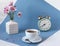 A Cup of fragrant tea with a bouquet of flowers in a white vase and a clock, close-up, side view-the concept of time for a