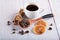 A cup of fresh Americano, a wooden spoon with coffee beans, cinnamon sticks and dried oranges