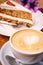 Cup of fresh cappuccino coffee with delicious piece of carrot cake on the wooden table