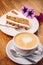 Cup of fresh cappuccino coffee with delicious piece of carrot cake on the wooden table