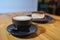 Cup of fresh cappuccino and snickers cheesecake on a blue saucer on a large bright wooden table