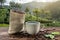 A Cup of fresh coffee and roasted beans in a bag on the table against the backdrop of a landscape of coffee plantations