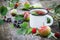 Cup of fruit tea with apples, pears, raspberries and black currant berries on wooden table outdoors.