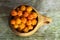 A cup full of cloudberries. Close-up of a wooden kuksa mug with cloudberries