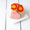 Cup full of pink gerbera flowers and heart shape cookie on whi