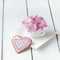 Cup full of pink mum flowers and heart shape cookie on white w