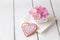 Cup full of pink mum flowers and heart shape cookie on white w