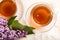 A cup of green tea against the background of a spring bouquet of lilacs on a textured background.