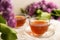 A cup of green tea against the background of a spring bouquet of lilacs on a textured background.