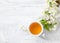 Cup of green tea and branch of blossom cherry on white wooden table