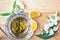 Cup of green tea with jasmine over light back. Beautiful composition. Top view of jasmine tea and jasmine flowers on wooden table