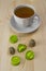 A cup of green tea on a wooden table. Pressed Chinese tea in the shape of a ball and heart, shiny green foil wrapper. Related tea
