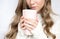 Cup in the hands of a girl in a sweater on a white background