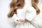 Cup in the hands of a girl in a sweater on a white background