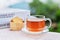 Cup of herbal infusion tea with biscuits basket, stacking books and nature green background.