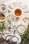 Cup of herbal tea with tea bags , teapot with fresh medical herbs and honey on white table, top view. Healthy lifestyle concept