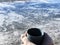 Cup of hot beverage in hands close-up across frozen lake. Winter landscape. Outdoor activity. Wintertime. Camping. Outdoor equipme