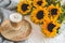 Cup with hot cappuccino, gray pastel woolen blanket, sunflowers, bedroom