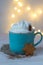 A cup of hot chocolate with cream with gingerbread in star shape on bokeh background