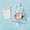 Cup of hot cocoa or chocolate, stylish fir tree and wish list on turquoise confetti background top view. Christmas concept.