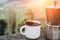 Cup hot coffee and coffee maker on background of nature during the sunset
