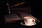 Cup of hot coffee, copper cezve and open Torah page on black wood table in the dark. Closeup