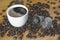 Cup of hot coffee and ground coffee in capsules from coffee beans on a wooden table of a rustic kitchen. Smoke and aroma