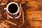 Cup of hot coffee, star anise, cinnamon sticks and scattered coffee beans on wooden table. Top view