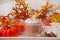 Cup of hot creamy cocoa with froth on the white tray with autumn leaves and pumpkins on the background