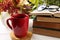 Cup with hot drink, stack of books and viburnum on white wooden windowsill indoors. Autumn atmosphere