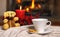 Cup of hot drink teddy bear candle in red Christmas decoration on cozy knitted plaid in front of warm fireplace. Holiday Christmas