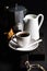 Cup of hot espresso, creamer with milk, cantucci and moka coffee pot on a rustic wooden board
