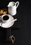 Cup of hot espresso, creamer with milk and cookies on dark rustic wooden board over black background, copy space